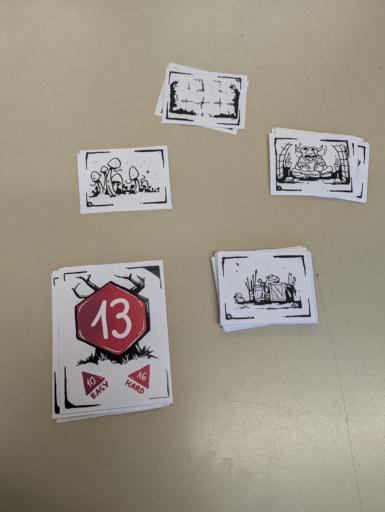 Cut out paper cards for the index card RPG. There are monsters, loot and dungeon dressings drawn on them in broad strokes like with a sharpie