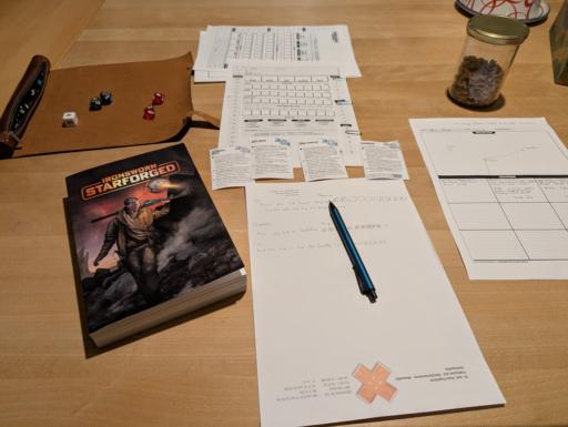 Character sheet, connection notes and a sector map are spread out on a wooden table. To the left there is a dice mat showing d10s and one d5. Below is the Ironsworn Starforged rulebook.