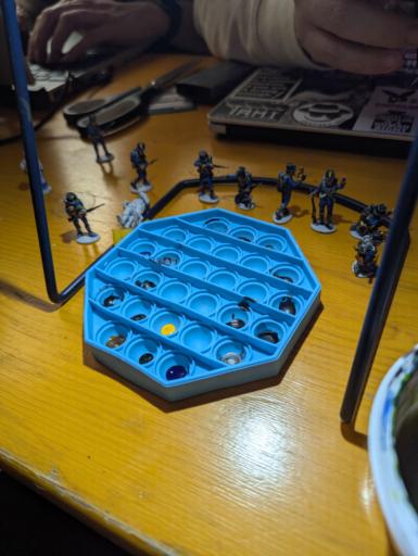 A collection of half painted Napoleonic miniatures around a silicone pop fidget toy used as a palette for paints