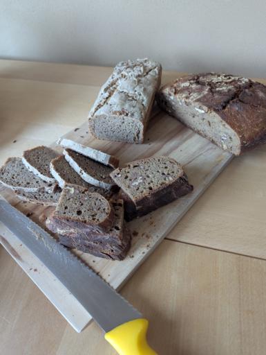 Zwei aufgeschnittene Laib Brot, eines ein Kastenbrot, DSS andere rund mit Walnüssen